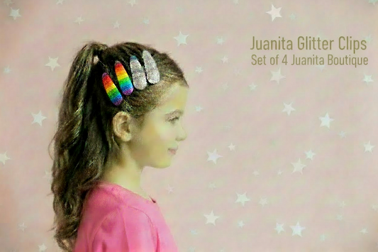 Child with colourful hair clips in a ponytail against a pink background