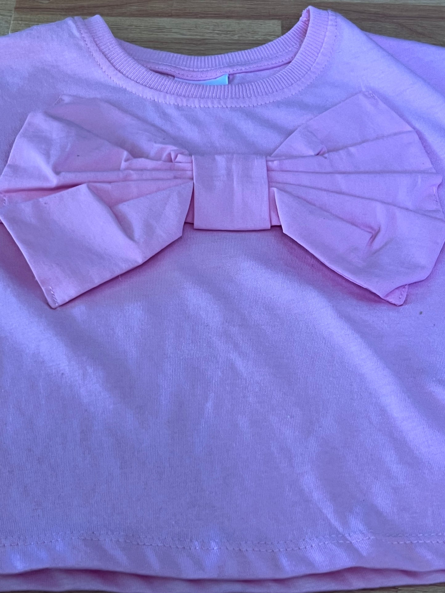 Pink top with a bow detail on a wooden surface
