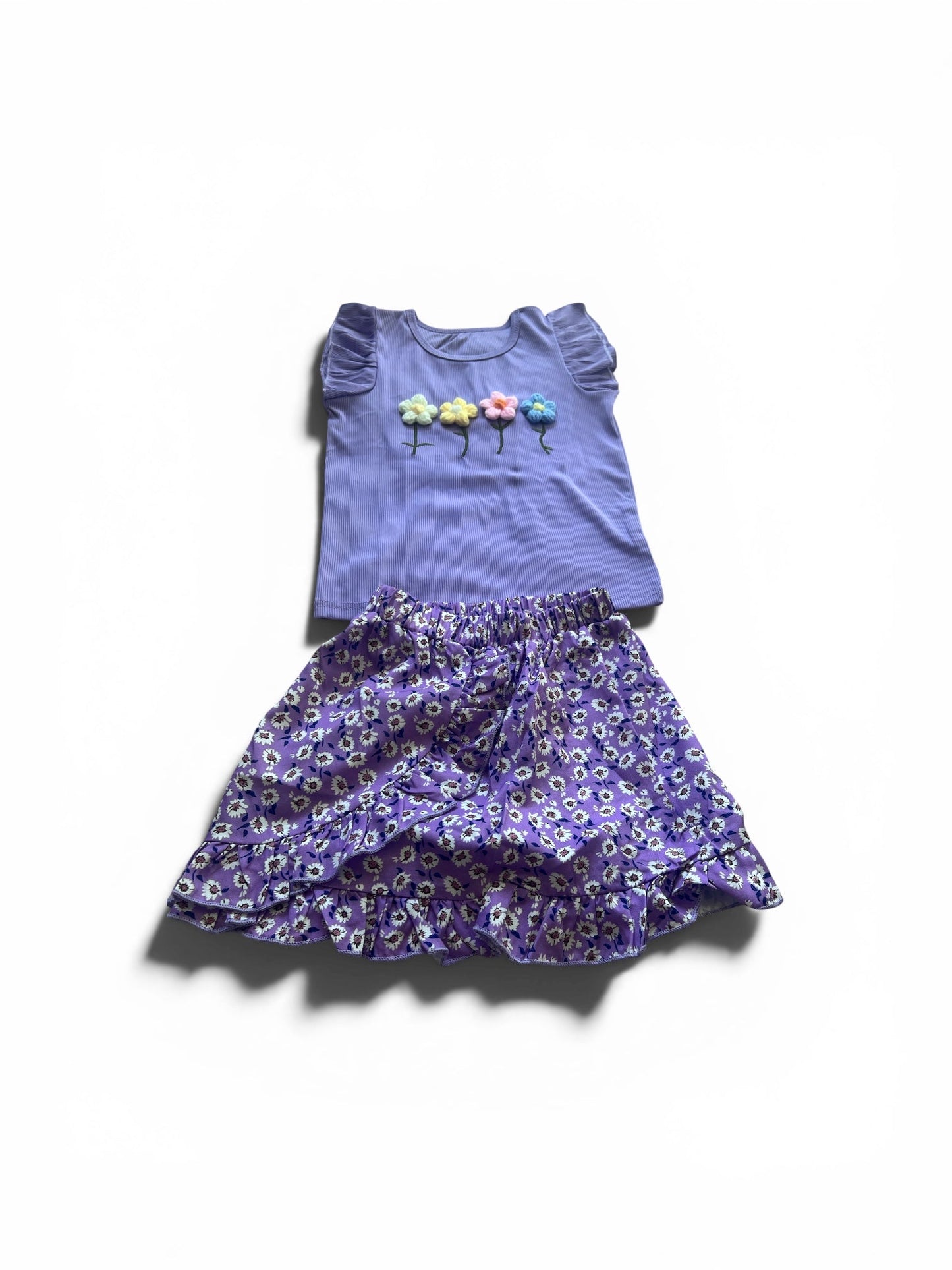 Purple top with floral designs and matching skirt on a white background