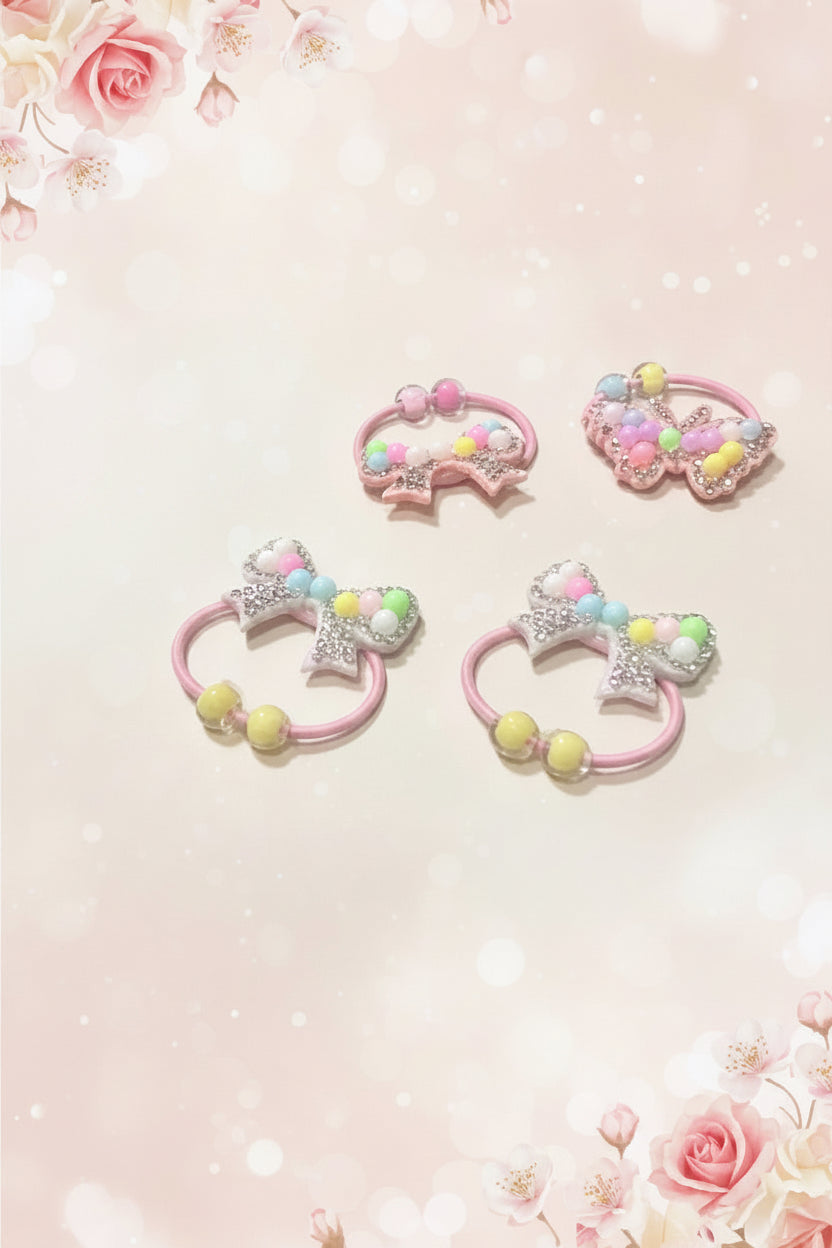 Set of four colorful hair ties with bows on a light pink background with floral decorations.