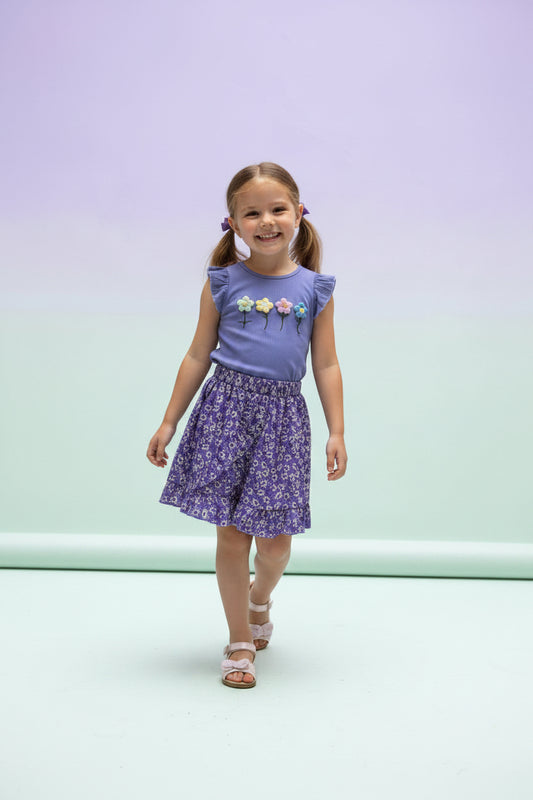 Young girl wearing a purple outfit with floral elements on a gradient background