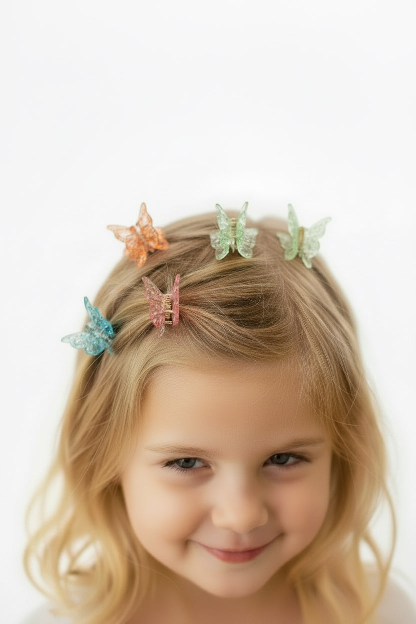 Young girl with blonde hair wearing colorful butterfly hair clips on a white background
