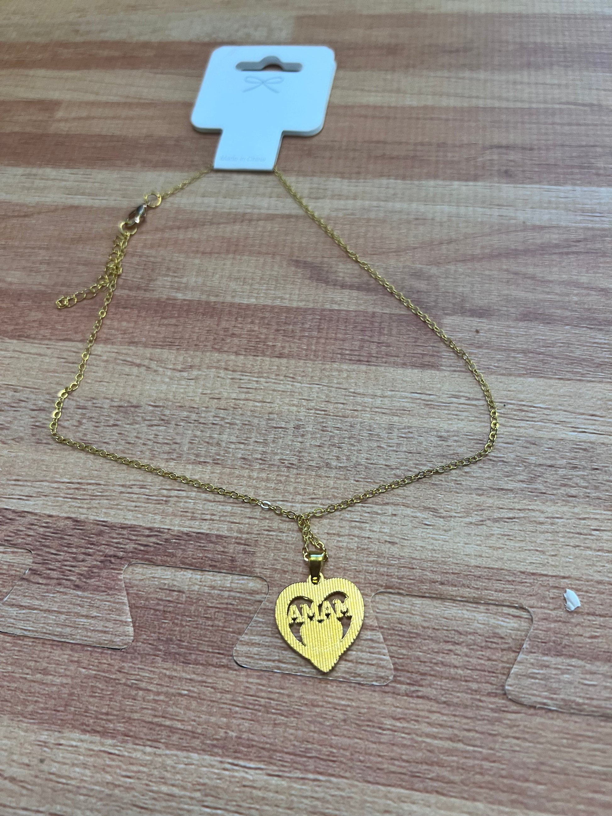 Gold necklace with a heart-shaped pendant on a wooden surface back vew
