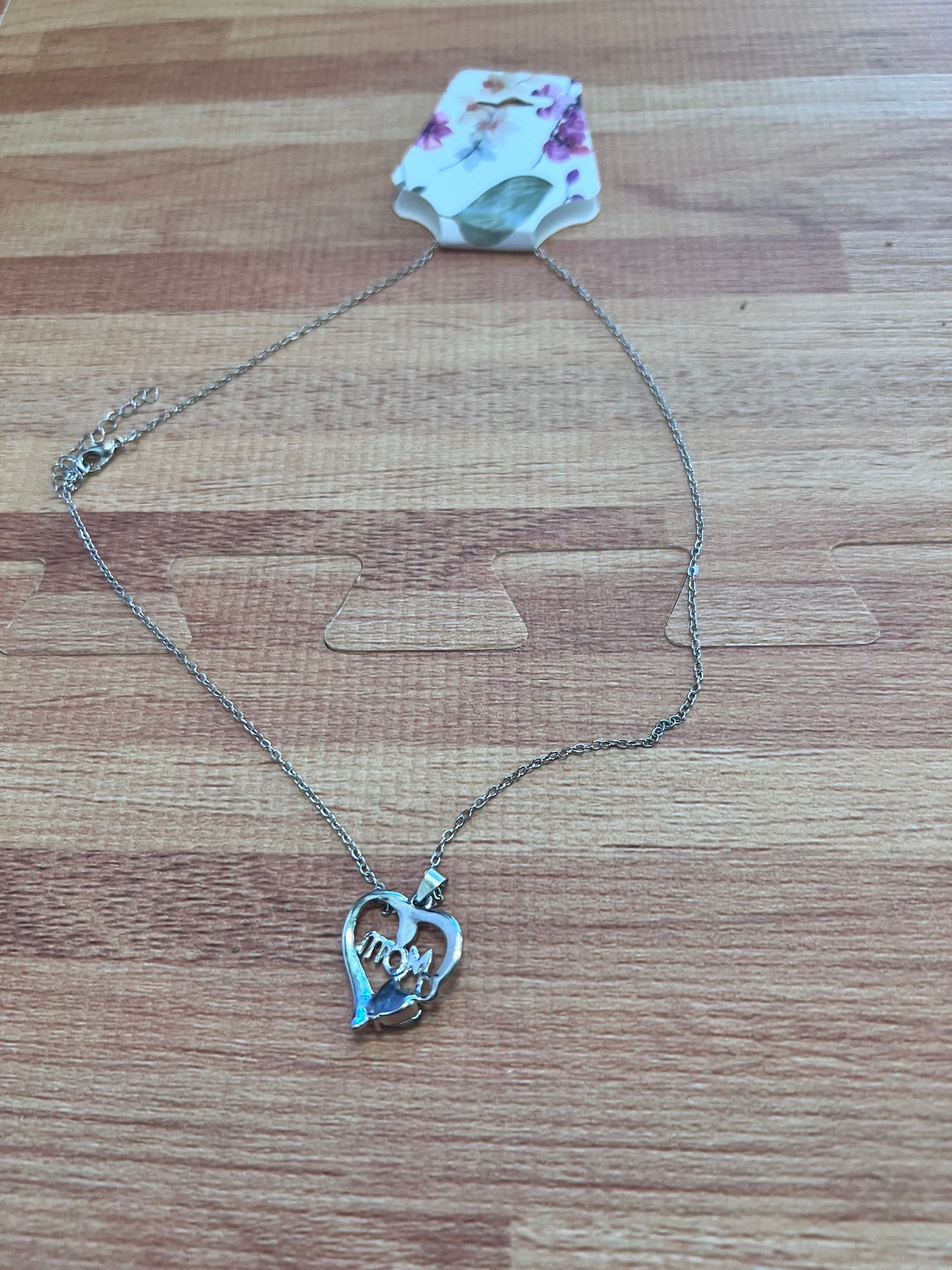 Silver necklace with a heart-shaped pendant on a wooden surface
