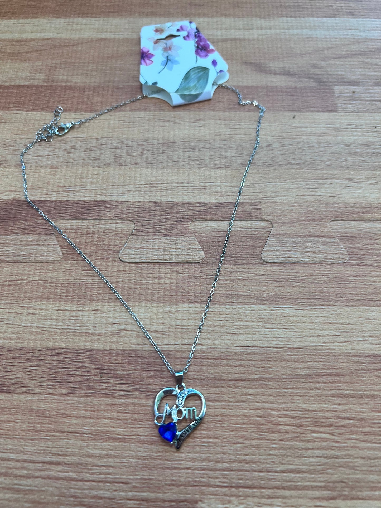 Necklace with a heart-shaped pendant and blue gem on a wooden surface