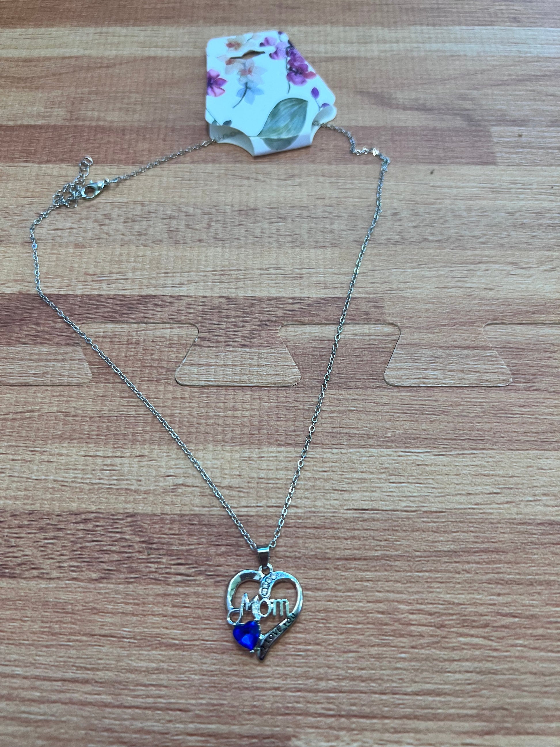 Necklace with a heart-shaped pendant and blue gem on a wooden surface