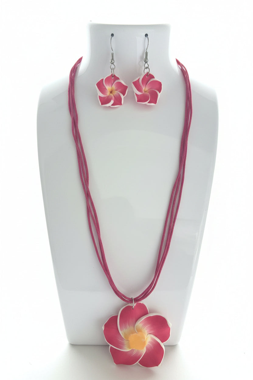 Pink floral necklace and earrings on a white stand.