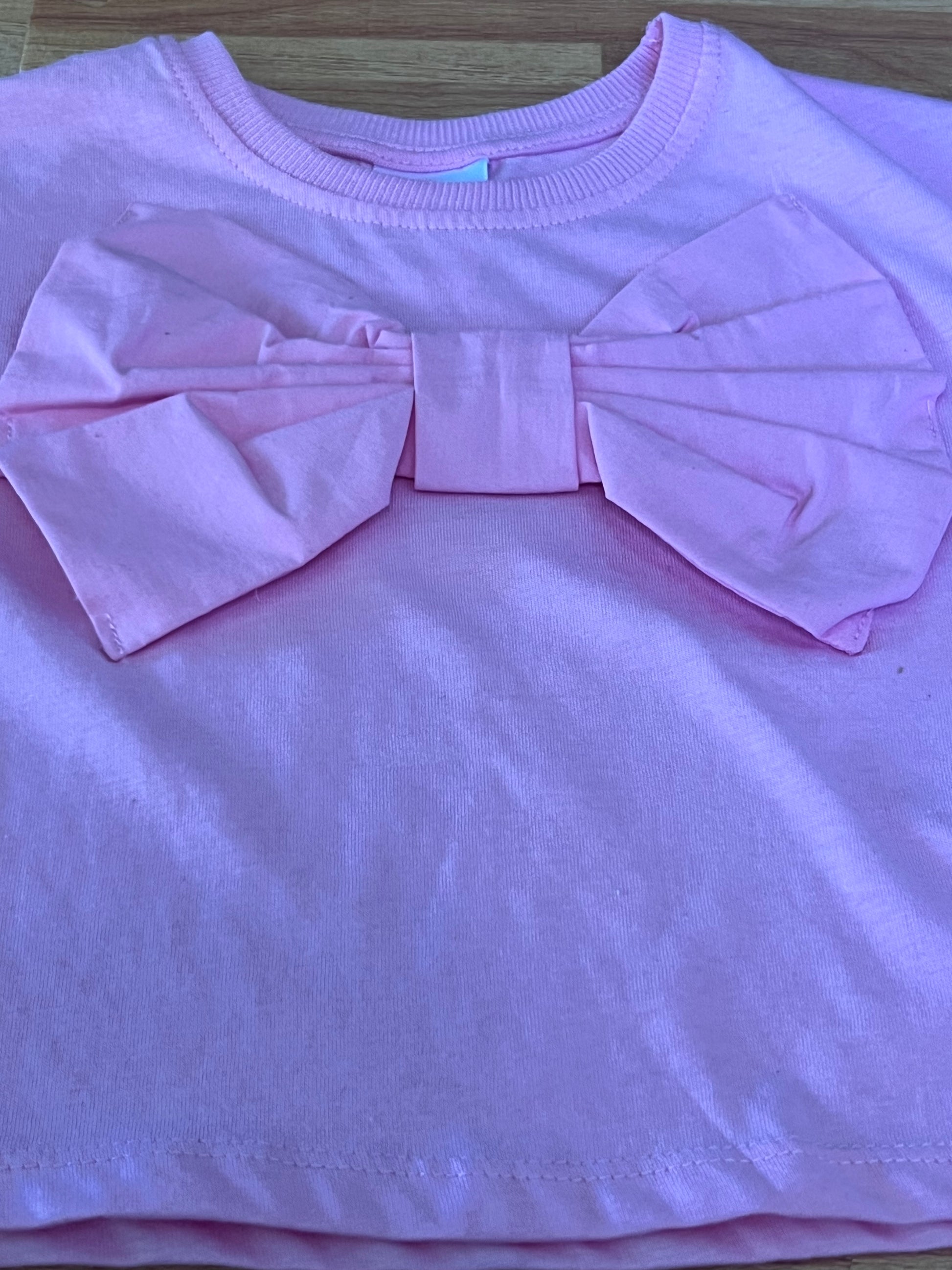 Pink top with a bow detail on a wooden surface